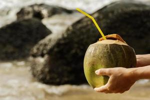 femme avec une boisson à la noix de coco sur la plage tropicale photo