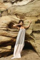 jeune femme en belle robe longue à côté de falaises de sable photo