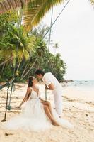 heureux jeune couple marié célébrant leur mariage sur la plage photo