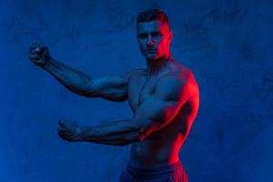 homme musclé posant dans la lumière colorée photo