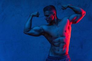 homme musclé posant dans la lumière colorée photo