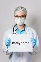 femme médecin tient du papier avec le hashtag stayhome photo