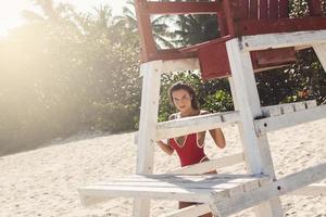 femme sexy en maillot de bain rouge à côté de la tour de maître nageur sur la plage photo