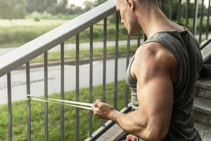 homme musclé pendant l'entraînement avec un élastique de résistance dans une rue. photo