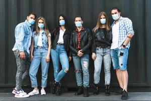 groupe d'amis portant des masques de prévention lors de leur réunion à l'extérieur. photo