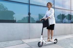 jeune et belle femme d'affaires fait du scooter électrique photo