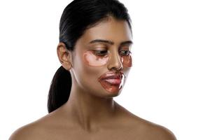 belle femme indienne avec des patchs hydratants pour les yeux et un masque à lèvres sur son visage photo