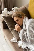 femme avec un symptôme d'écoulement nasal allongé sous la couverture à la maison photo