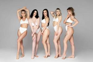 groupe de femmes différentes portant de la lingerie sur fond gris photo