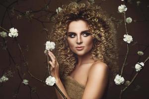 jolie jeune femme avec une coiffure afro et un beau maquillage avec beaucoup de fleurs blanches photo