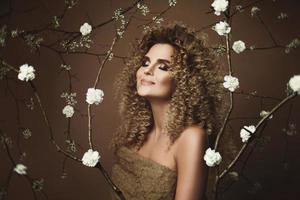 jolie jeune femme avec une coiffure afro et un beau maquillage avec beaucoup de fleurs blanches photo