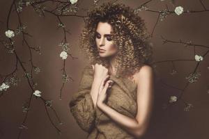 jolie jeune femme avec une coiffure afro et un beau maquillage avec beaucoup de fleurs blanches photo