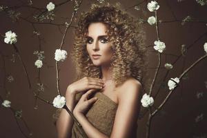 jolie jeune femme avec une coiffure afro et un beau maquillage avec beaucoup de fleurs blanches photo