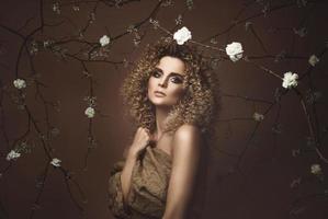 jolie jeune femme avec une coiffure afro et un beau maquillage avec beaucoup de fleurs blanches photo