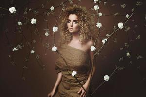 jolie jeune femme avec une coiffure afro et un beau maquillage avec beaucoup de fleurs blanches photo