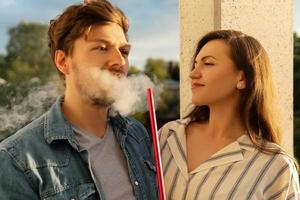 jeune couple heureux fumant le narguilé sur un balcon photo