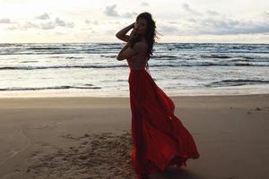 superbe femme vêtue d'une belle robe rouge sur la plage photo