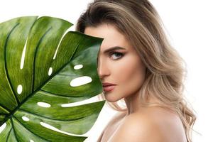 belle femme avec une peau lisse tenant une feuille tropicale verte photo