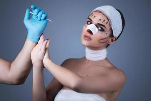 une femme enveloppée de bandages et de cicatrices est préparée pour une autre opération. photo