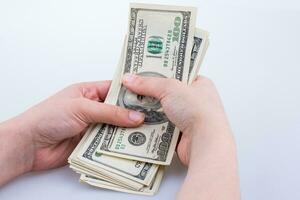 main humaine tenant des billets en dollars américains sur fond blanc photo