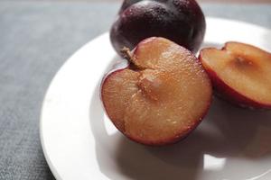 tranches de prunes rouges fraîches sur une table en bois photo