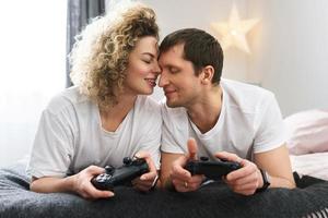 un couple avec des manettes joue à la console de jeux vidéo à la maison photo