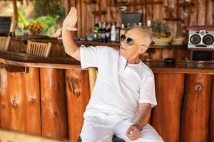 heureux homme âgé assis au bar de la plage photo