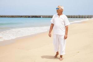 heureux homme âgé marchant sur la plage photo