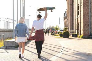 couple d'adolescents avec un longboard pendant leur rendez-vous dans une ville photo