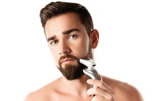 bel homme barbu utilise une tondeuse électrique photo