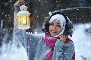 jeune femme avec une lanterne aux chandelles dans sa main marchant dans la forêt d'hiver enneigée photo