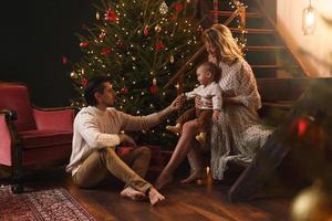 une jeune famille heureuse célèbre noël ou le nouvel an. photo