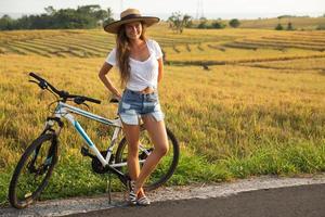 femme heureuse avec un vélo sur le bord de la route photo