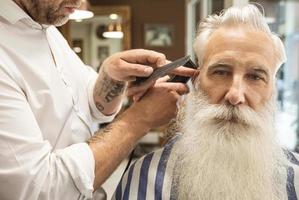 coiffeur faisant une coupe de cheveux élégante pour un beau vieil homme photo