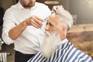 coiffeur faisant une coupe de cheveux élégante pour un beau vieil homme photo