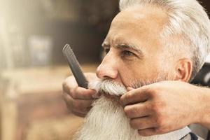 bel homme âgé se coiffant et taillant sa barbe photo