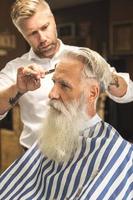 coiffeur faisant une coupe de cheveux élégante pour un beau vieil homme photo