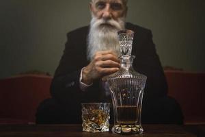 homme âgé beau et barbu buvant du whisky photo