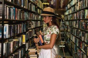 belle fille portant une tenue élégante à la recherche d'un livre intéressant dans la librairie vintage photo