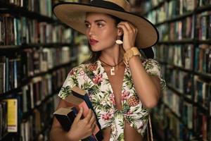 belle fille portant une tenue élégante à la recherche d'un livre intéressant dans la librairie vintage photo