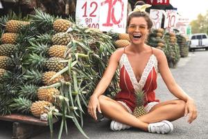 jeune et heureuse femme avec un tas d'ananas sur le marché thaïlandais local photo