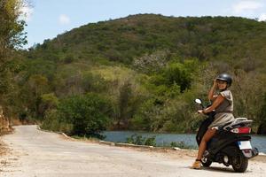 femme conduisant un scooter sur une ancienne route rurale dans les montagnes photo