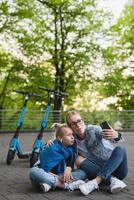 heureuse mère et fille prenant selfie pendant que les scooters électriques roulent photo
