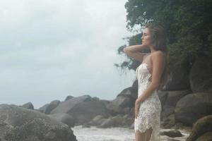 jeune femme vêtue d'une belle robe blanche pose sur la plage photo