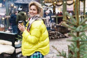 femme heureuse avec une tasse de boisson chaude sur le marché de Noël photo