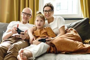 une famille heureuse joue à la console de jeux vidéo à la maison photo