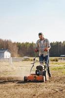 homme utilisant une machine d'aération pour la scarification et l'aération de la pelouse ou du pré photo