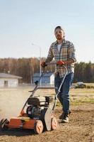 homme utilisant une machine d'aération pour la scarification et l'aération de la pelouse ou du pré photo