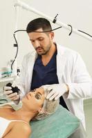 médecin dermatologue et cliente pendant le traitement de resurfaçage de la peau au laser photo