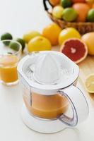 verre de jus d'orange, presse-agrumes et divers agrumes sur la table de la cuisine photo